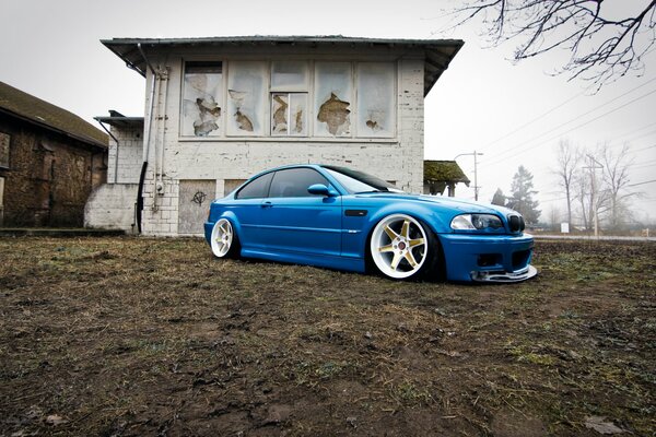 Синий BMW на фоне заброшенного дома