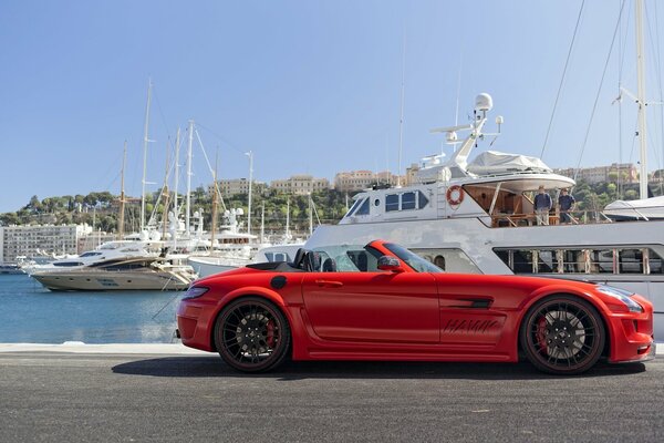 Red Mercedes-Benz on the ocean surrounded by yachts