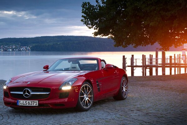 A chic red convertible on the background of water