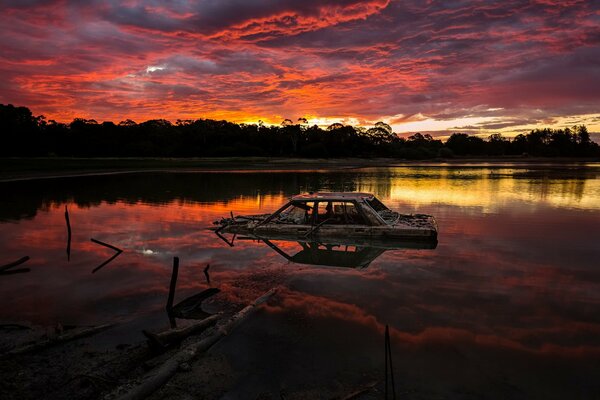 Coche ahogado en el lago durante la puesta del sol