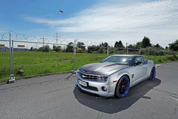 A gray Chevrolet at the airfield is waiting for the plane to land