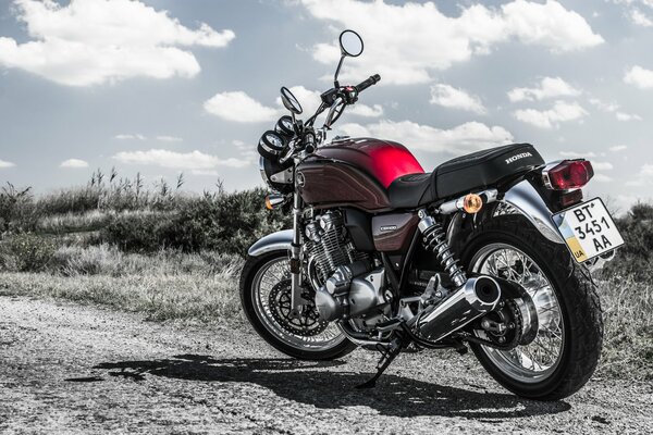 La moto Honda CB1100 se tient sur un chemin de terre