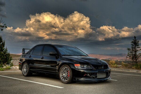 Mitsubishi evolution azul oscuro contra un cielo tormentoso