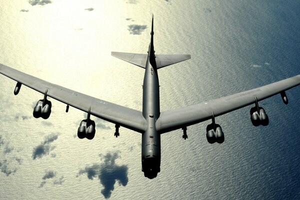 A big plane is flying over the water in the clouds