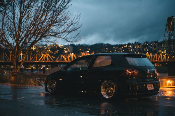 Volkswagen golf in front of the bridge of the night city by the river