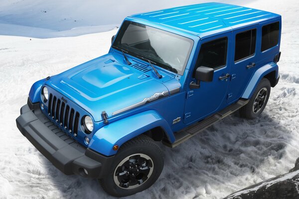 Jeep Wrangler azul en las montañas cubiertas de nieve