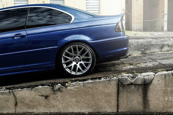 BMW blu scuro su sfondo muro di pietra