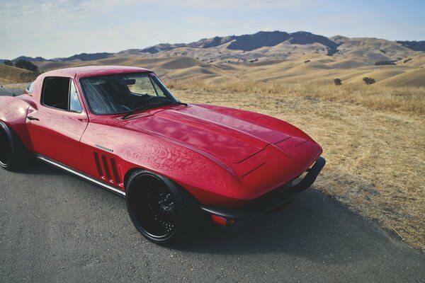 Retro Chevrolet red car on a background of yellow steppe and hills