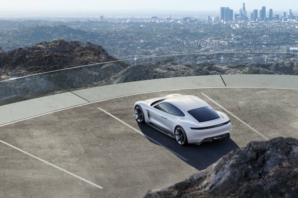 Ein weißer Porsche steht auf einer Aussichtsplattform mit Blick auf die Metropole