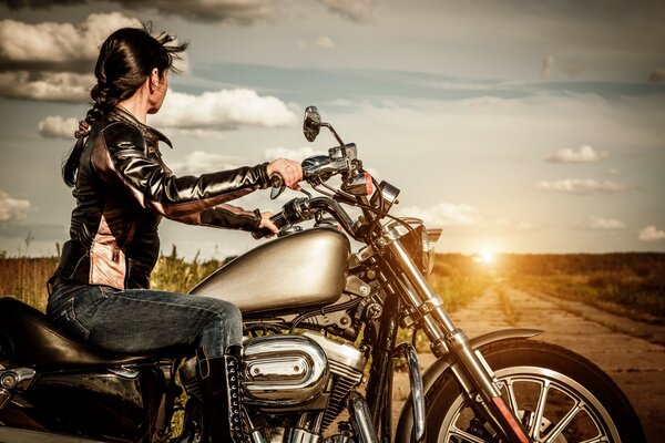 Dziewczyna na motocyklu składająca się w zachód słońca