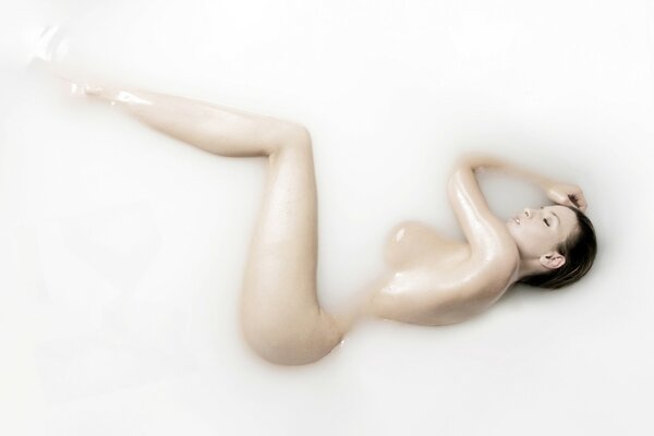 Naked brunette bathes in milk