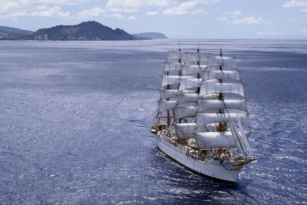 Ein Schiff mit weißen Segeln durchforstet die Wellen des Ozeans