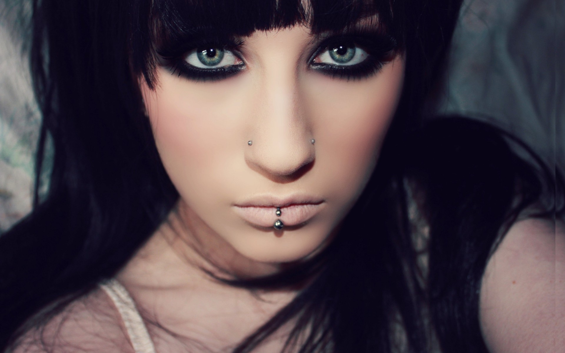 a woman girl brunette piercing grey close up face