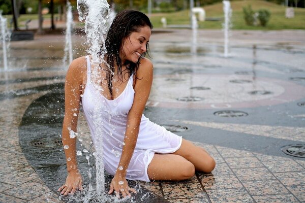 A girl in a white dress is bathing in a fountain