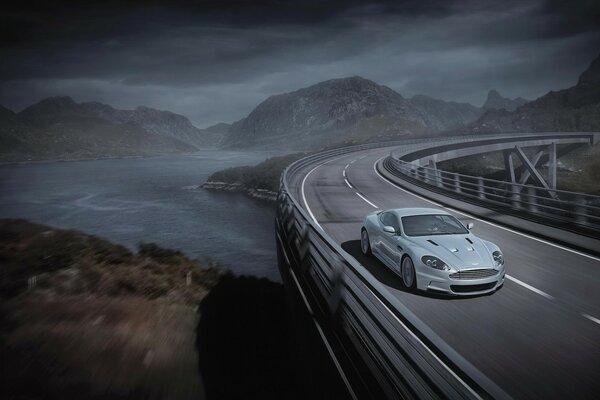 The handsome Aston Martin checks the strength of the bridge running away into the mountains with a ribbon