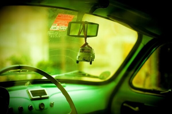 A miniature toy beetle hangs on the windshield mirror in the old Volga