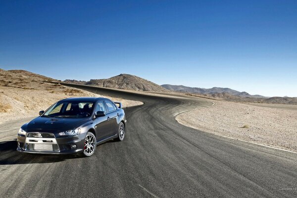 A black Mitsubishi car on a deserted road