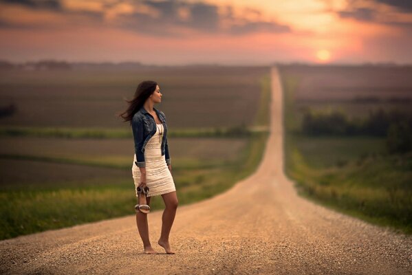 A barefoot girl is waiting on the road