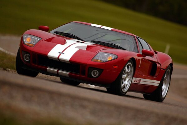 A red and white Ford GT passes a section of road