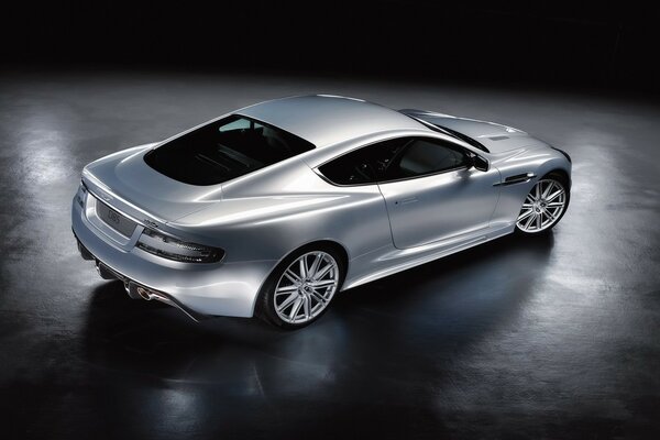 A silver Aston Martin DBS stands in the middle of the room