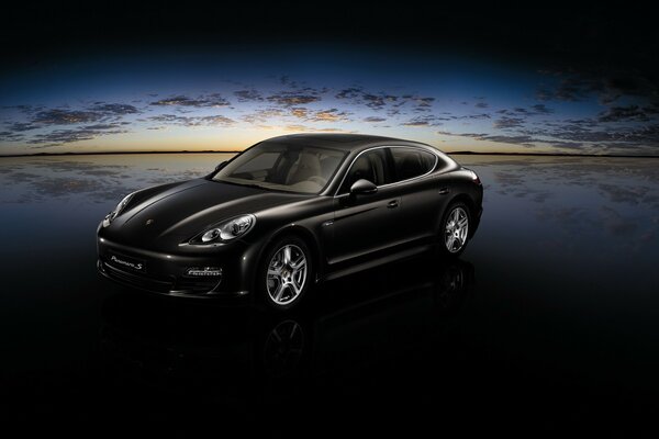 Porsche negro en la costa al atardecer