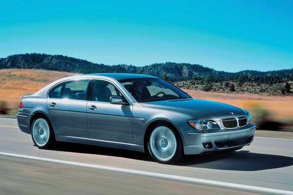 A silver BMW car is driving on the road