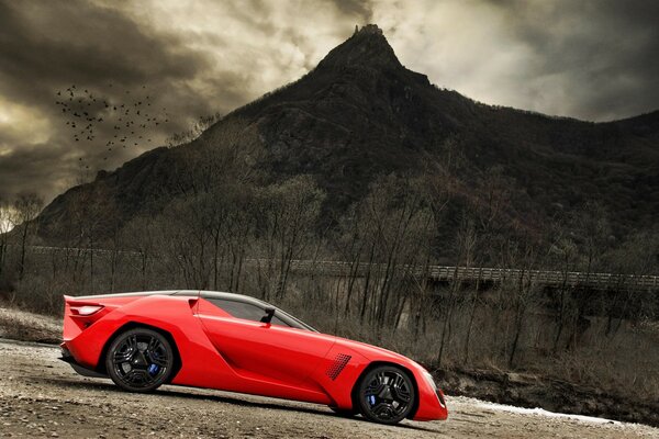 Una concept car rossa si erge su una ghiaia contro una montagna cupa