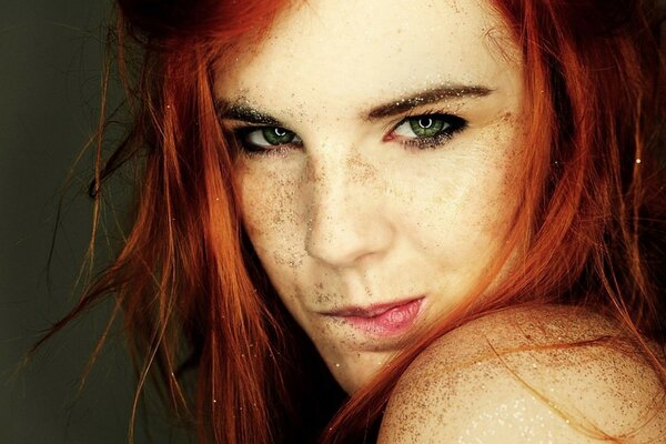 Das Gesicht einer Frau mit roten Haaren und Sand