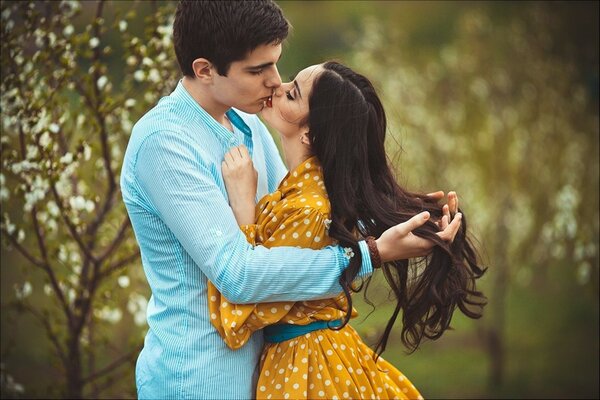 Sesión de fotos de enamorados. Un beso en el fondo de la naturaleza