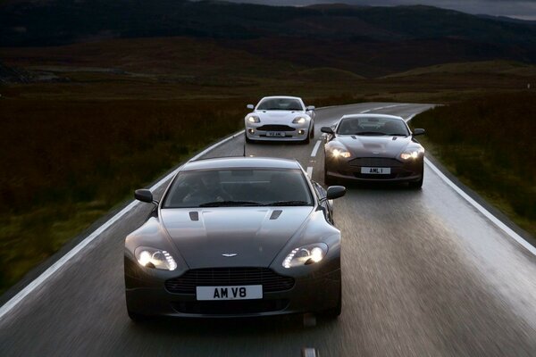 Three Aston Martin cars on the road