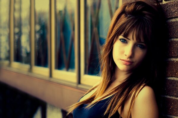 Blue-eyed girl against the wall with long hair