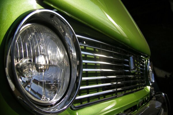 An unusual view of the headlights of a green car