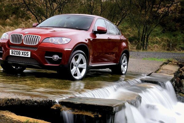 Bmw rojo en la naturaleza frente a la cascada