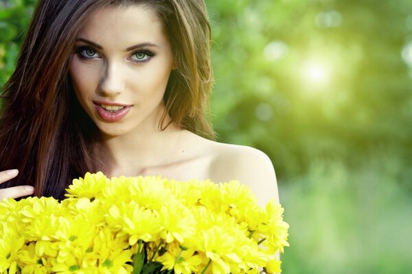 Hermosa mujer con flores amarillas en la mano