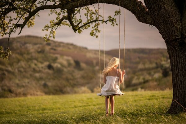 A girl in a white dress on a swing