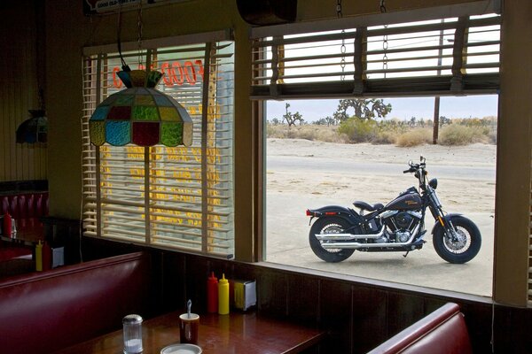 Black harley davidson in the window of a roadside cafe