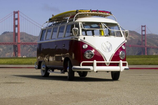 A red and white bus on the background of the famous Golden Gate Bridge. Cute bright Volkswagen bus