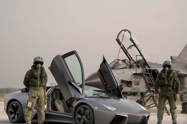 The pilots of the plane in full gear next to the lamborghini
