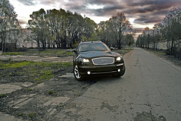 Black Infiniti car on a background of trees