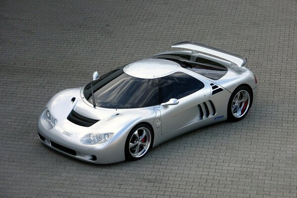 Silver car on asphalt with brickwork