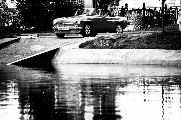 Black and white photo with an image of a car by the water
