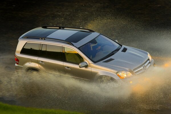 The Mersedes company car drives through the water surface at full speed