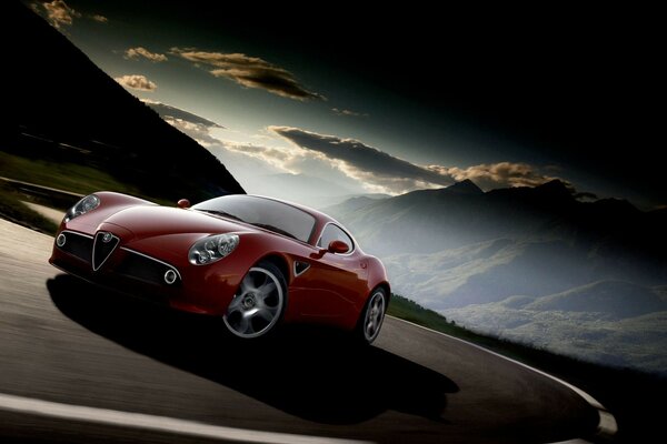 Czerwony samochód Alfa Romeo na drodze w górach