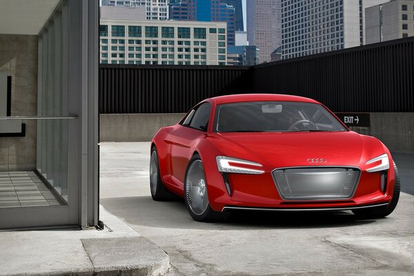 A red Audi E-tron stands in a multi-level parking lot