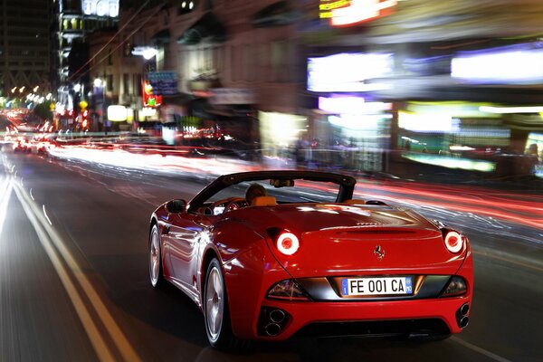 La Ferrari rossa di notte ad alta velocità corre lungo la strada