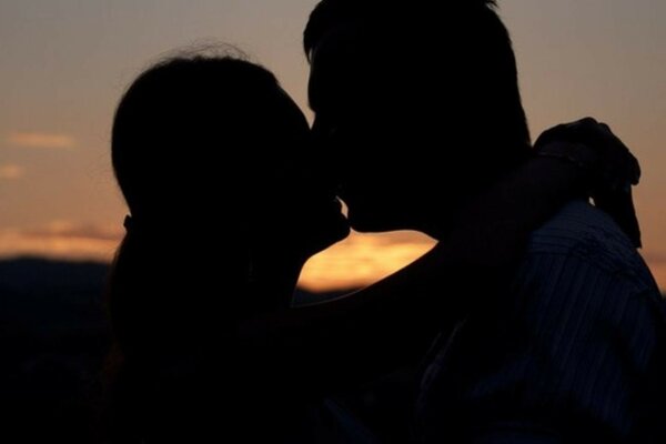 Romantic kiss on the background of the setting sun