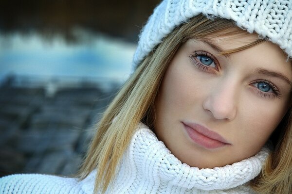 Chica de ojos azules con un suéter blanco y un sombrero