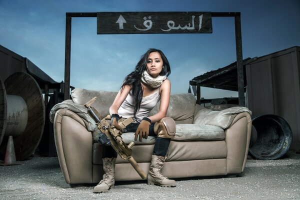 A girl with a machine gun is sitting on the couch