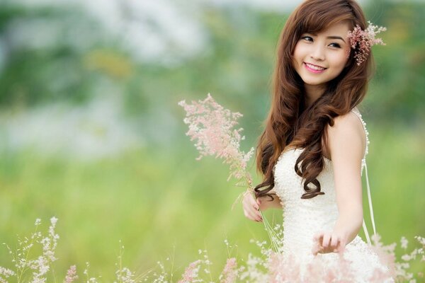 Bella asiatica in campo con bouquet