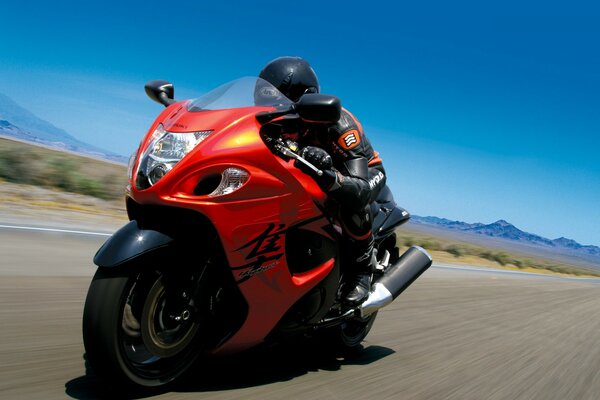 Mann auf einem leuchtend roten Motorrad, ein Motorrad mit hoher Geschwindigkeit fahren